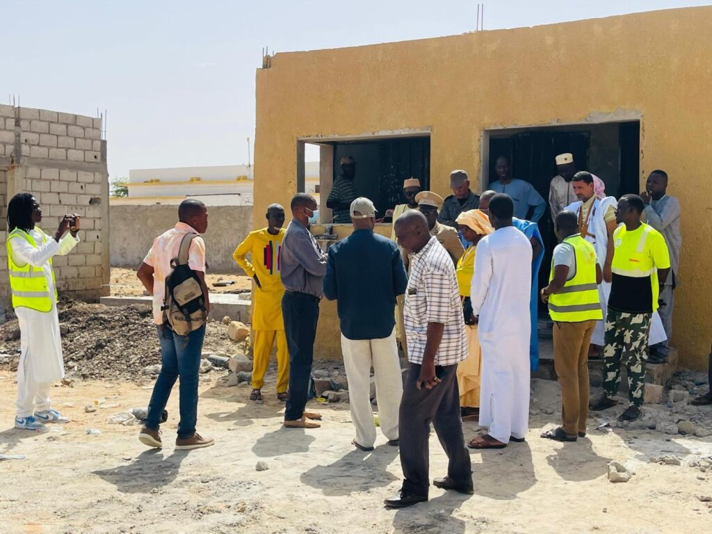 Visite du chantier de l'école avec les ouvriers en gilets de sécurité et les officiels