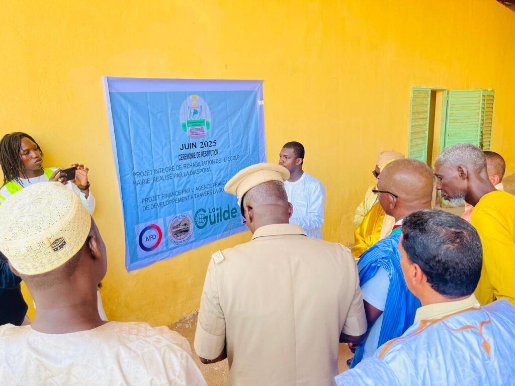 Officiels et membres devant la banderole du projet soutenu par La Guilde