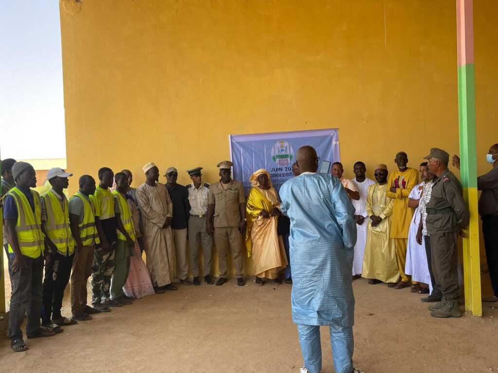 Photo de groupe des participants devant l'école rénovée et la banderole du projet